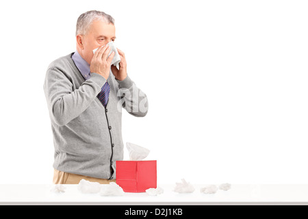 Mann, die Nase mit einem Feld von Gewebe auf einem Tisch isoliert auf weißem Hintergrund Stockfoto