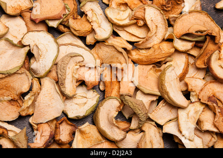 Scheiben von getrockneten Äpfeln als Hintergrund auf schwarz aus Holz Stockfoto