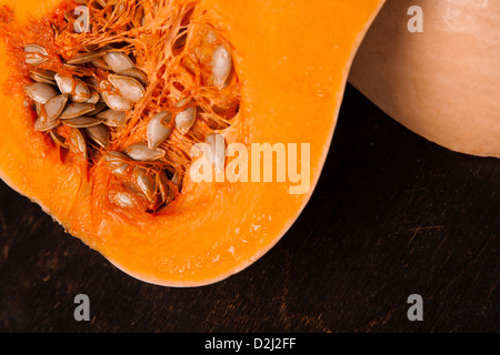 halbe frische Orange Kürbis auf schwarzem Hintergrund aus Holz Stockfoto