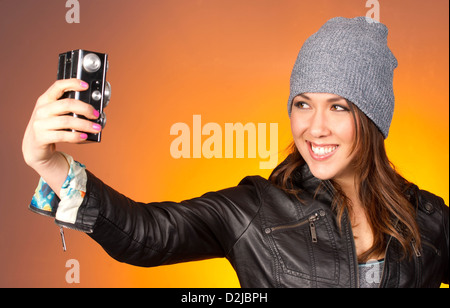 Hip-Frau rastet ein Selbstporträt mit Vintage-Kamera in einer horizontalen Komposition Stockfoto