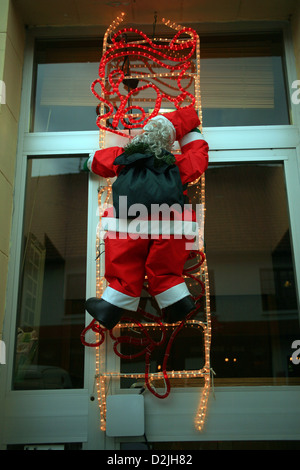 Father Christmas Kletter Leiter außen Dekoration auf Gebäude in Licques, Nord-Frankreich Stockfoto