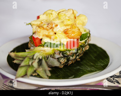 Frischer Salat mit Garnelen, Gemüse und Sauce in große Ananas auf den weißen Teller Stockfoto