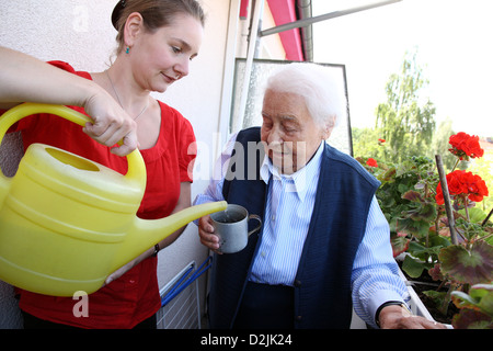 Berlin, Deutschland, eine junge Frau, die eine ältere Frau zu helfen, beim Gießen von Blumen Stockfoto