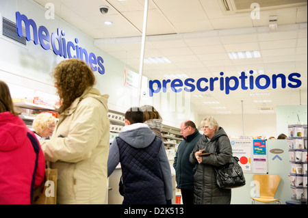 Rezepte-Zähler in einem Stiefel Shop in Cwmbran, South Wales, UK. Menschen, die über die Theke Medikamente warten. Stockfoto