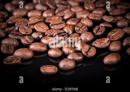 Frisch geröstete Kaffeebohnen auf schwarzen Glanz-Tisch. Nahaufnahme Foto Stockfoto