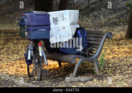 Tokyo, Japan, Symbol Foto Armut, ein Mann auf einer Parkbank liegen und Zeitung lesen Stockfoto