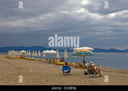 Zeile der Liegestühle und Sonnenschirme an einem bewölkten Tag am Strand Stockfoto