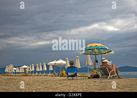 Zeile der Liegestühle und Sonnenschirme an einem bewölkten Tag am Strand Stockfoto