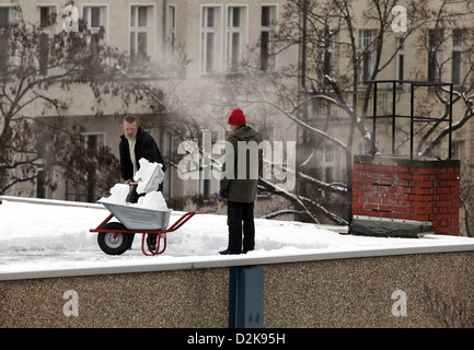 Berlin, Deutschland, Mann Schneeschaufeln aus einem Flachdach Stockfoto