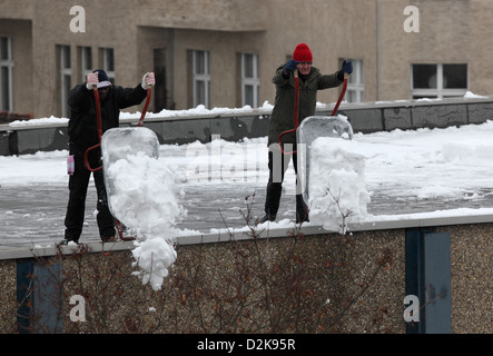 Berlin, Deutschland, Männer entfernen Schnee von einem Flachdach Stockfoto