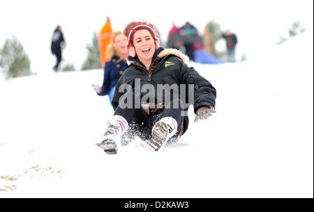 Zwei junge Frauen genießen Rodeln zusammen unten ein Schnee bedeckt Hügel an einem kalten Wintertag. Stockfoto