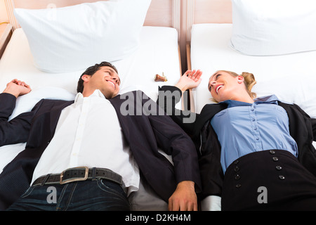 Junges Paar in den Hotel Zimmer Und lächelnd auf dem Bett liegend Stockfoto