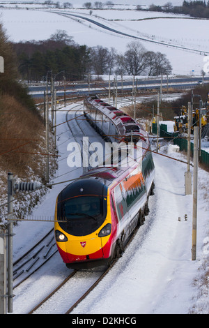 Gleise, Züge & Passagiere auf Virgin Pendolino Passagier, Hochgeschwindigkeitszug in Beckfoot, Cumbria bei winterlichen Bedingungen mit schneebedeckter Strecke. VEREINIGTES KÖNIGREICH Stockfoto