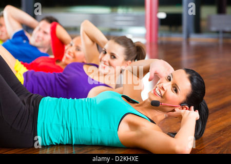 Fitness-Gruppe mit Trainer im Fitnessstudio tut Magen knirscht für sport Stockfoto