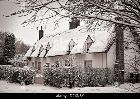 Schneebedeckte Reetdachhaus, leichte Sepia Tönung Stockfoto
