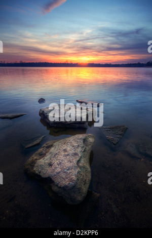 Ein schöner Sonnenuntergang leuchtet der Himmel über einem See Stockfoto