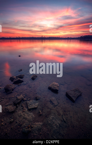 Ein schöner Sonnenuntergang leuchtet der Himmel über einem See Stockfoto