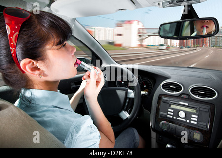 Frauen machen Lippen am Steuer des Autos Stockfoto