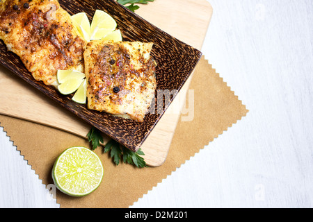 Gebratener weißer Fisch, serviert mit Kalk, auf hölzernen Geschirr Stockfoto