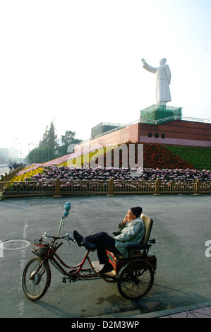 Mann sitzt auf einem Fahrrad unter Mao Statue, china Stockfoto