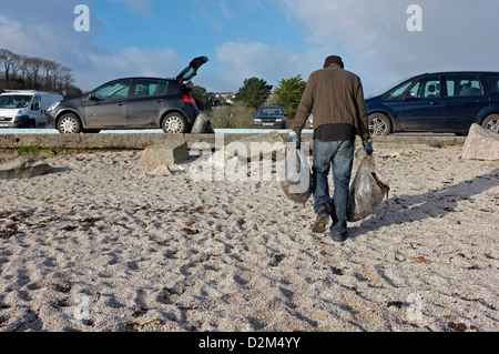 Ein Mann trägt Algen vom Strand in Cornwall, Großbritannien Stockfoto