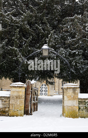 Kidlignton, Oxfordshire St Mary's Kirche gate Eingang mit alten Lampe und Eiben (Taxus Baccata), es ist Winter und schneit. Stockfoto