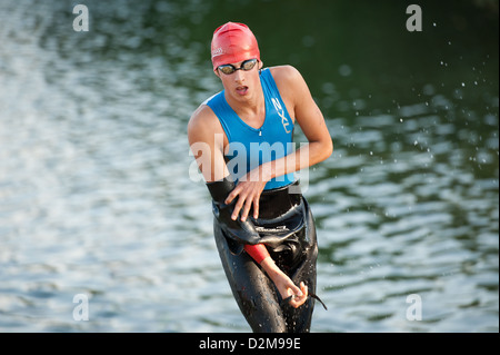 Erste Schwimmer aus Übergang ausgeführt und ausziehen Neoprenanzug mit blauen Trisuit unter See im Hintergrund Stockfoto