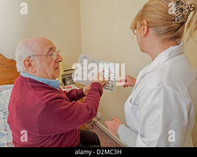 älterer Mann mit Betreuer und Blisterpackung von Medikamenten Stockfoto