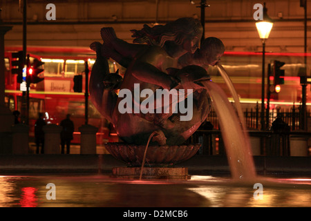 Eine Nacht Blick auf eine Wasserskulptur in einem Brunnen am Trafalgar Square mit Bussen vorbei in den Hintergrund Stockfoto