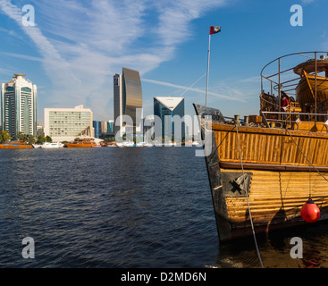 Dubai Creek bei Neubauten inc Bank of Dubai und Chamber of Commerce (rechts) mit einer Dhau Boot im Vordergrund. Stockfoto