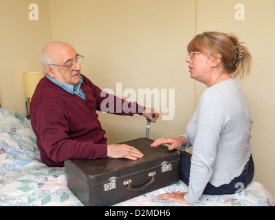 älterer Mann setzte sich auf Bett im Gespräch mit Tochter Stockfoto