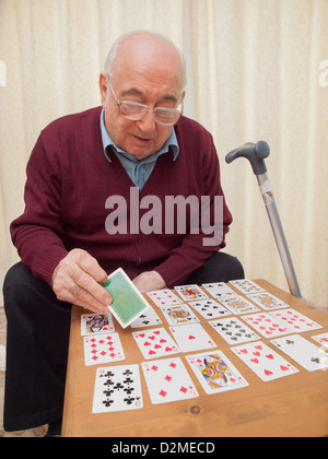 ältere Menschen sitzen Mann Spielkarten auf eigene Faust Stockfoto