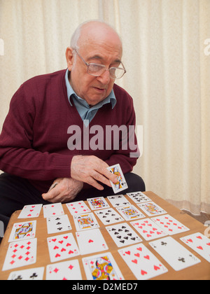ältere Menschen sitzen Mann Spielkarten auf eigene Faust Stockfoto