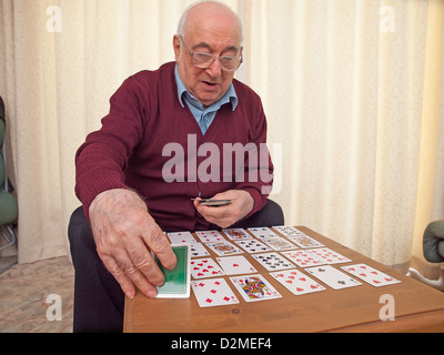 ältere Menschen sitzen Mann Spielkarten auf eigene Faust Stockfoto