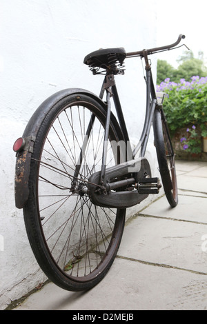 Rostige antiken Damen Schleife Rahmen (oben sitzen und betteln) Fahrrad, Fahrrad ist ein altes englisches Landhaus gelehnt. Stockfoto