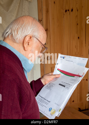 älterer Mann Haushalt Stromrechnungen zu betrachten Stockfoto