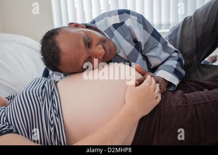 Schwangere weiße weibliche und schwarze männliche Herzschlag des Babys hören Stockfoto