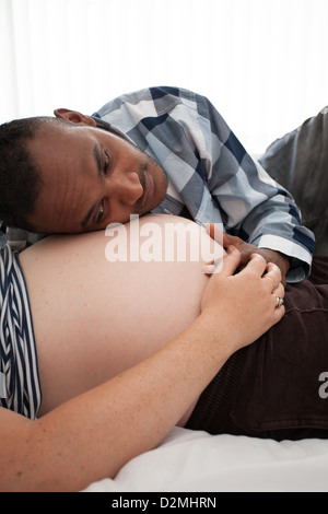 Schwangere weiße weibliche und schwarze männliche Herzschlag des Babys hören Stockfoto