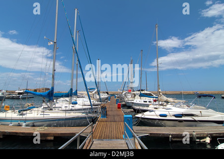 Weiße Yachten mit blauen Segel aufgereiht auf der Anklagebank Stockfoto