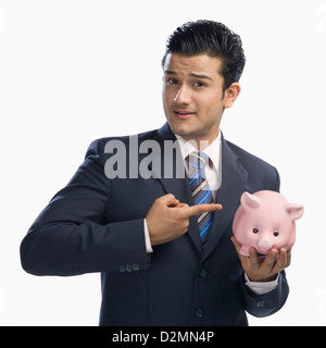 Geschäftsmann zeigte auf ein Sparschwein Stockfoto