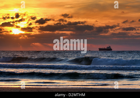 Wellen am Mittelmeer bei Sonnenuntergang auf einem Hintergrund schönen Himmel und die Sonne bricht durch die Wolken über Horizont. Stockfoto