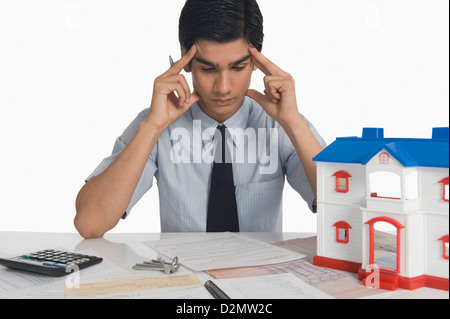 Immobilien mit Kopf in Händen sitzen in der Nähe ein vorbildliches Haus Stockfoto