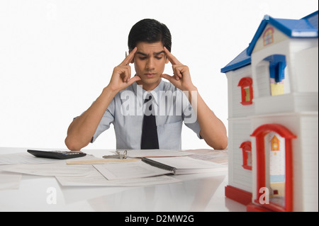 Immobilien mit Kopf in Händen sitzen in der Nähe ein vorbildliches Haus Stockfoto