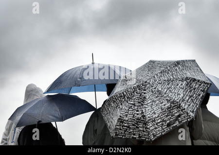 Eine Gruppe von Menschen, die Zuflucht vor dem Regen unter Sonnenschirmen in Paris Stockfoto