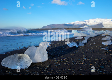 Eisberge auf vulkanische Sandstrand am Jökulsárlón mit Schnee auf den massiven Eiskappe des Vatnajökull hinter Island, Polarregionen Stockfoto