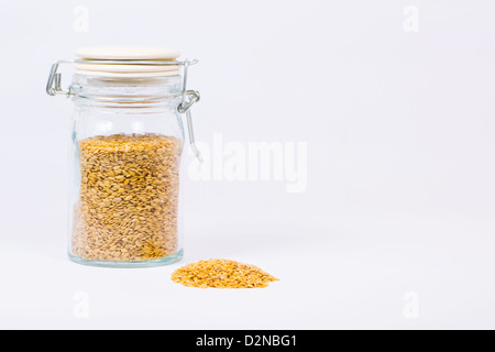 Goldenen Leinsamen in ein Glas jar vor einem weißen Hintergrund. Stockfoto