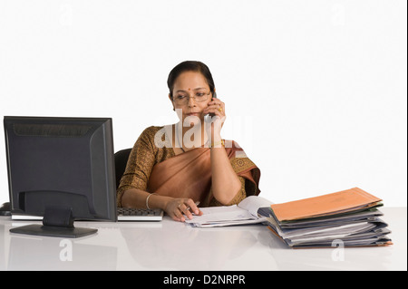 Geschäftsfrau am Schreibtisch sitzen und telefonieren mit einem Handy Stockfoto