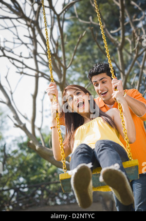 Mann eine Frau auf einer Schaukel schieben Stockfoto