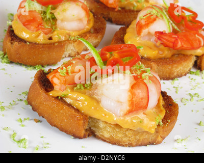 Kanapees Tiger Garnelen auf geröstetem Brot mit würziger Mayonnaise, in Scheiben geschnittene Chilischoten und Limettenschale. Stockfoto