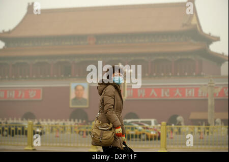 Eine Frau trägt eine Maske auf dem Tiananmen-Platz in dicker Nebel in Peking, 30. Januar 2013. Stockfoto